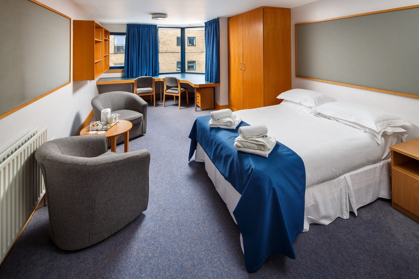 Double room ensuite at Christ's College, Cambridge, with a double bed, armchairs and a desk by the window.